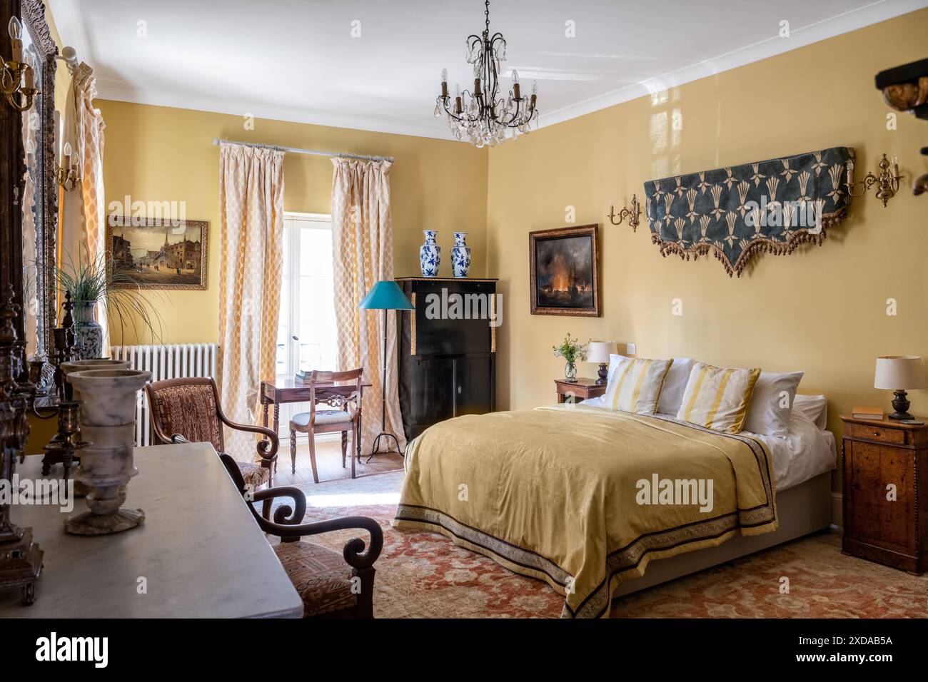 Yellow bedroom with antique furniture and wall hanging in renovated stone-built hotel particulier dating from 1770 in Saulieu, Burgundy, France. Stock Photo