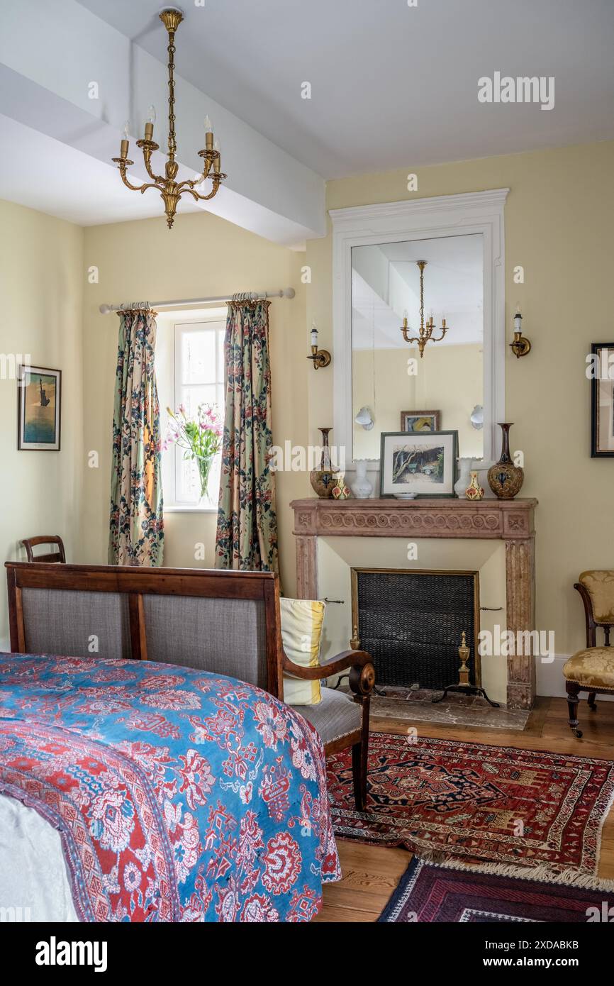 Decorative fireplace with contrasting fabrics in bedroom of renovated stone-built hotel particulier dating from 1770 in Saulieu, Burgundy, France. Stock Photo