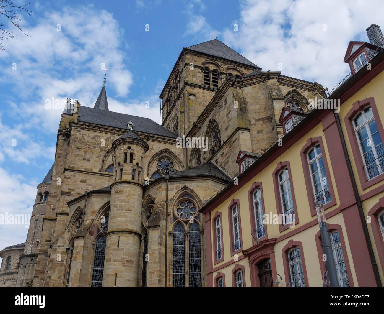 Large gothic church with numerous windows, historic buildings and blue sky, trier, germany Stock Photo