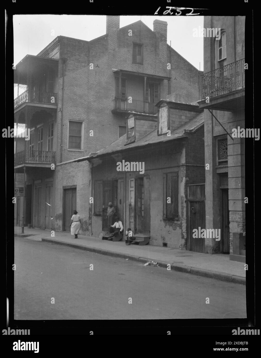 View from across street of a man and child sitting on steps and a woman