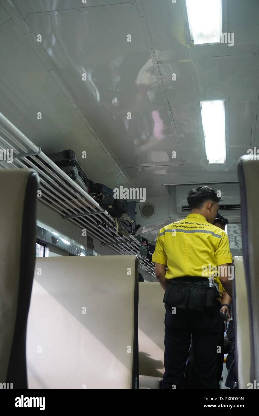 Train Captain Check A train officer wearing a yellow shirt walks in a train carriage to ...
