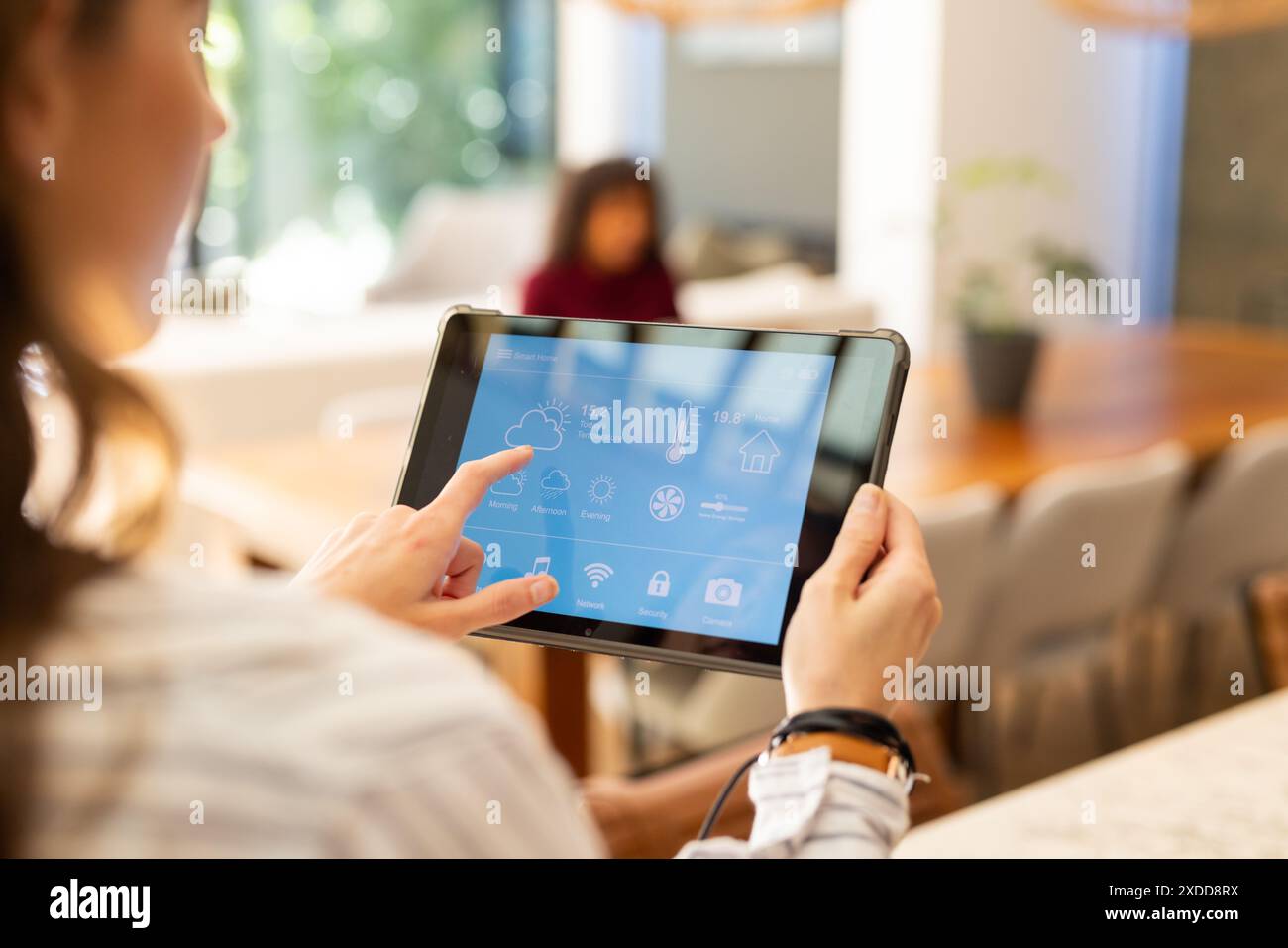 Woman using tablet to control smart home settings in living room Stock Photo