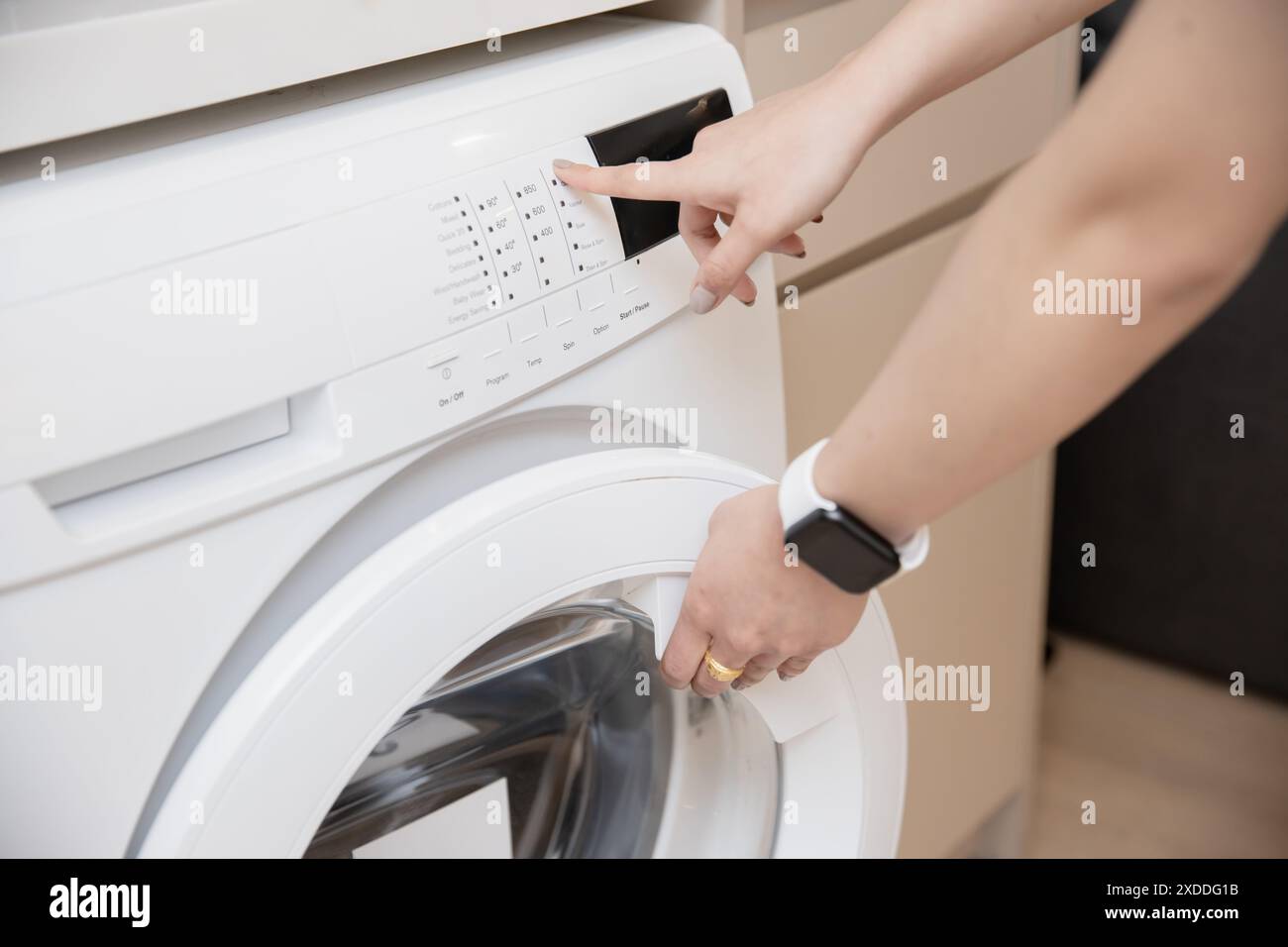 closeup people home house maid using front load washing machine touch press program button Stock Photo