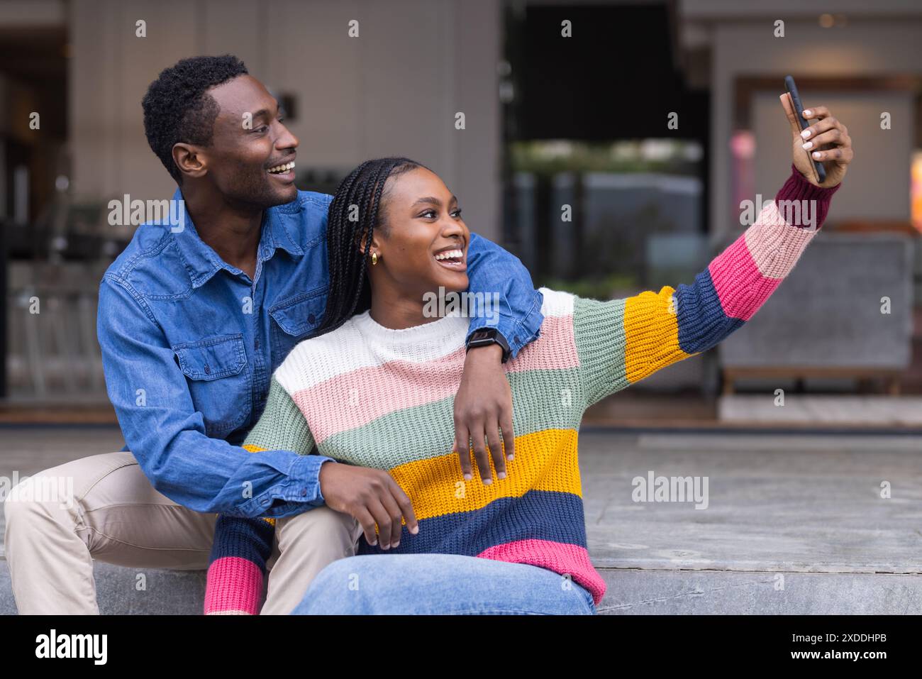 Young African American couple sitting together, taking selfie with smartphone Stock Photo