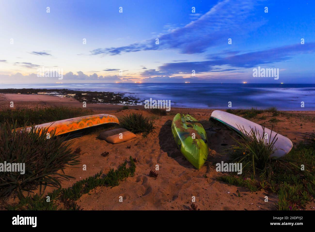 Canoes on sand side of Hams beach on Australian Pacific coast in moonlight at sunrise. Stock Photo