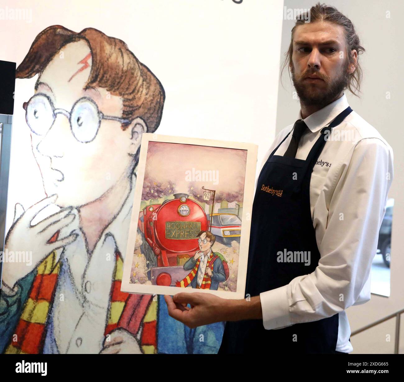 New York, New York, USA. 21st June, 2024. A handler holds artist Thomas Taylor's Original Cover Art for Harry Potter and the Philosopher's Stone 1997 estimate $400,000 -600,000 seen on display at the press preview for Sotheby's June 2024 Fine Book and Manuscripts Auctions held at Sotheby's New York. (Credit Image: © Nancy Kaszerman/ZUMA Press Wire) EDITORIAL USAGE ONLY! Not for Commercial USAGE! Stock Photo