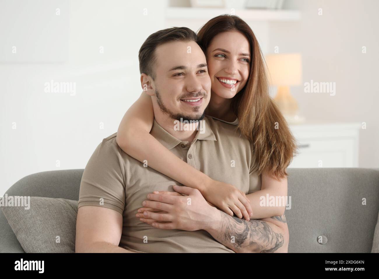 Woman hugging her happy boyfriend on sofa at home Stock Photo - Alamy
