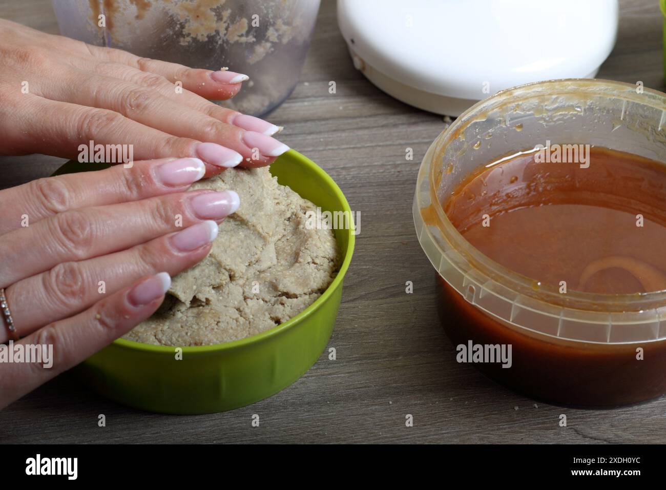 A woman seals hands cooked halva from honey, peanuts and sunflower ...