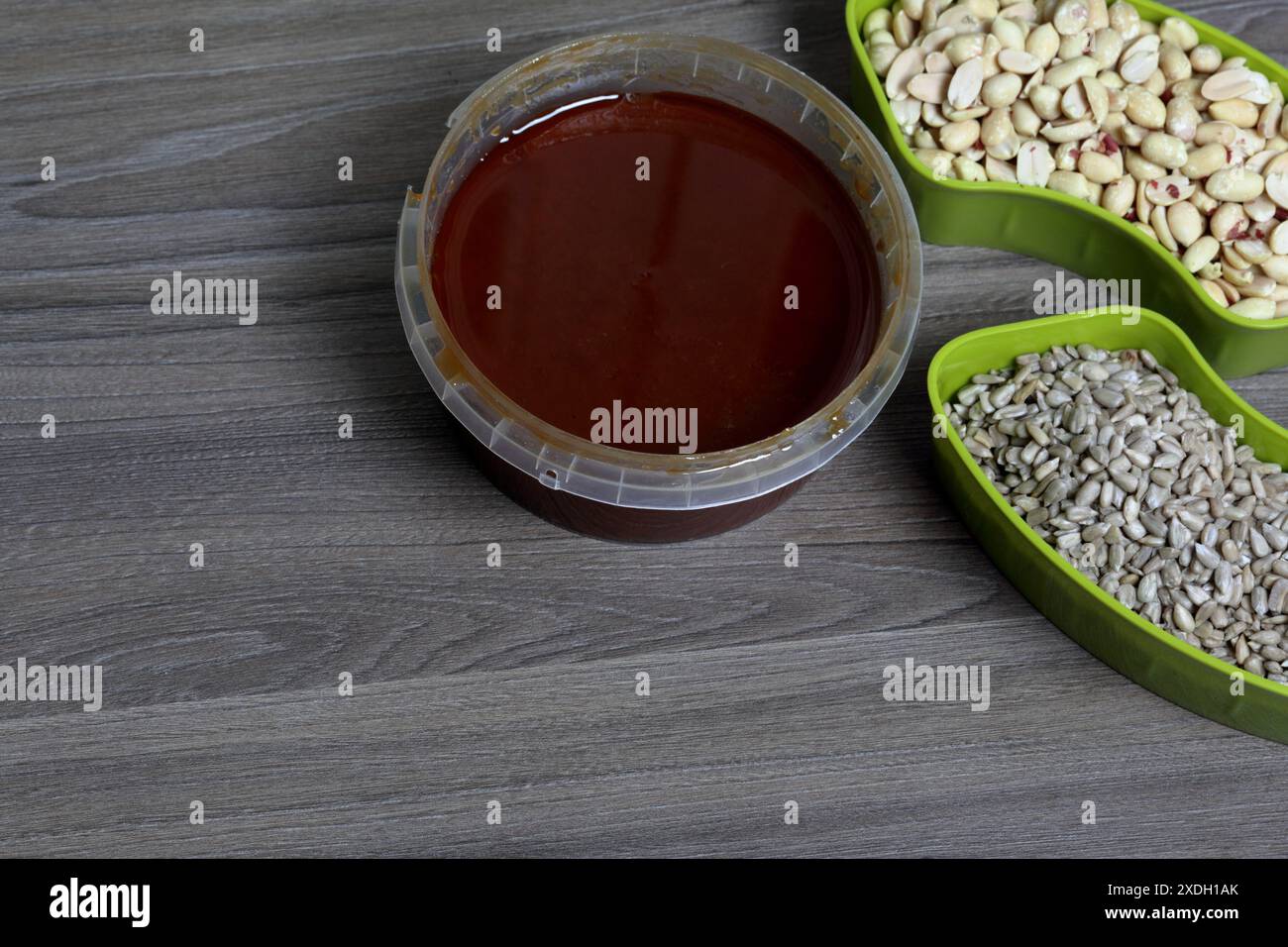 Honey in a container. Next to separate containers of peanuts and ...