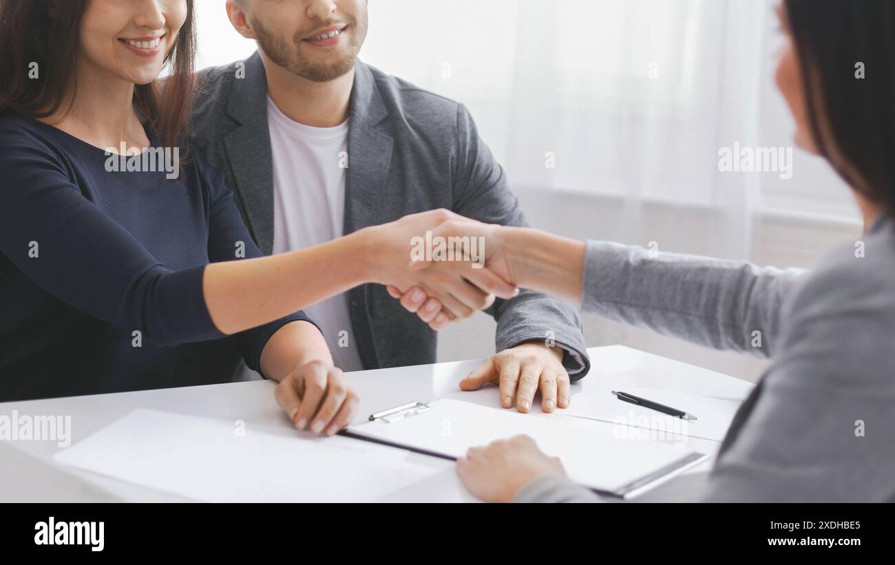 Couple Shaking Hands With Financial Advisor During a Meeting, Cropped Stock Photo