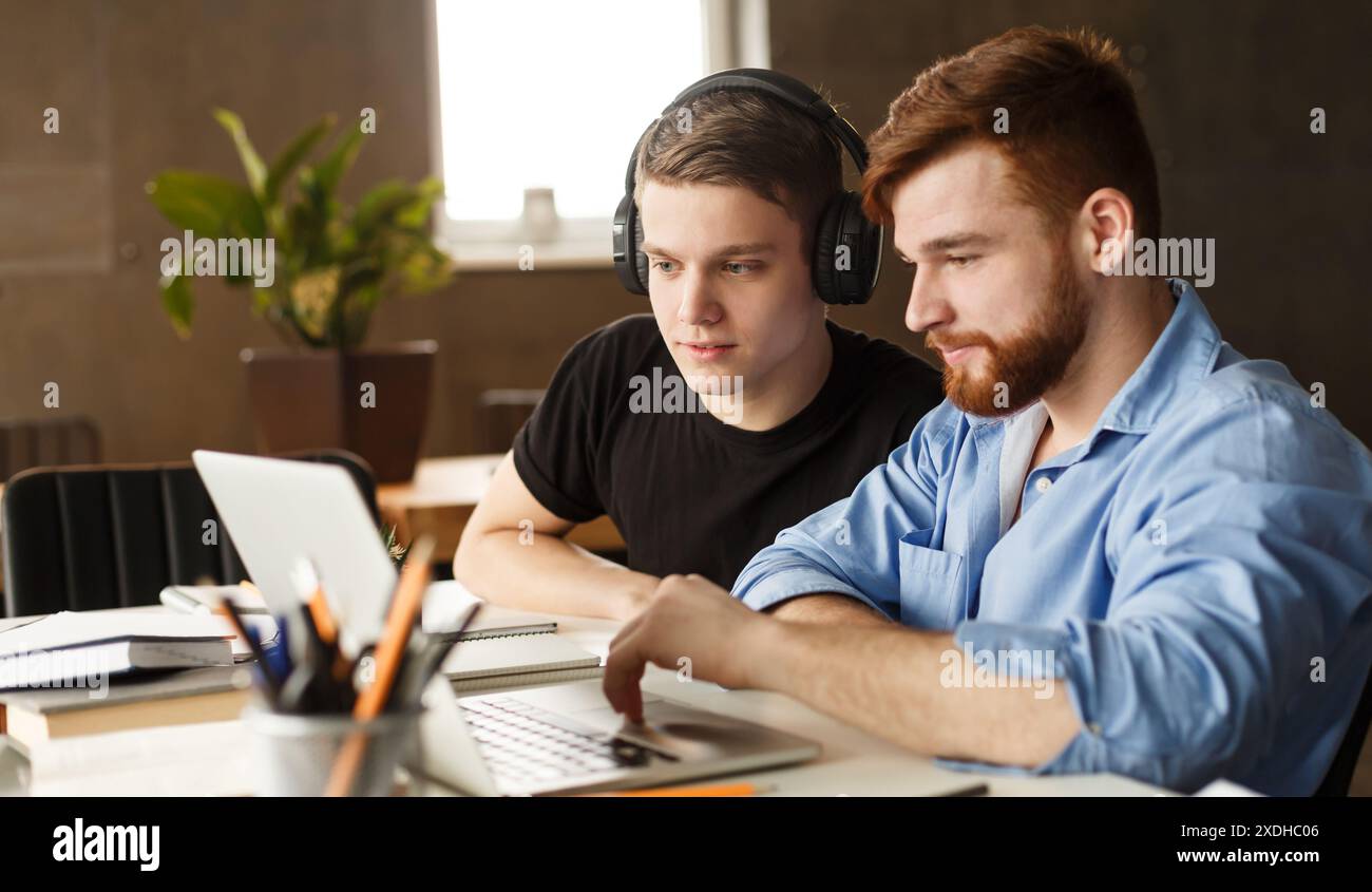 Two Men Working on a Laptop in Library Stock Photo