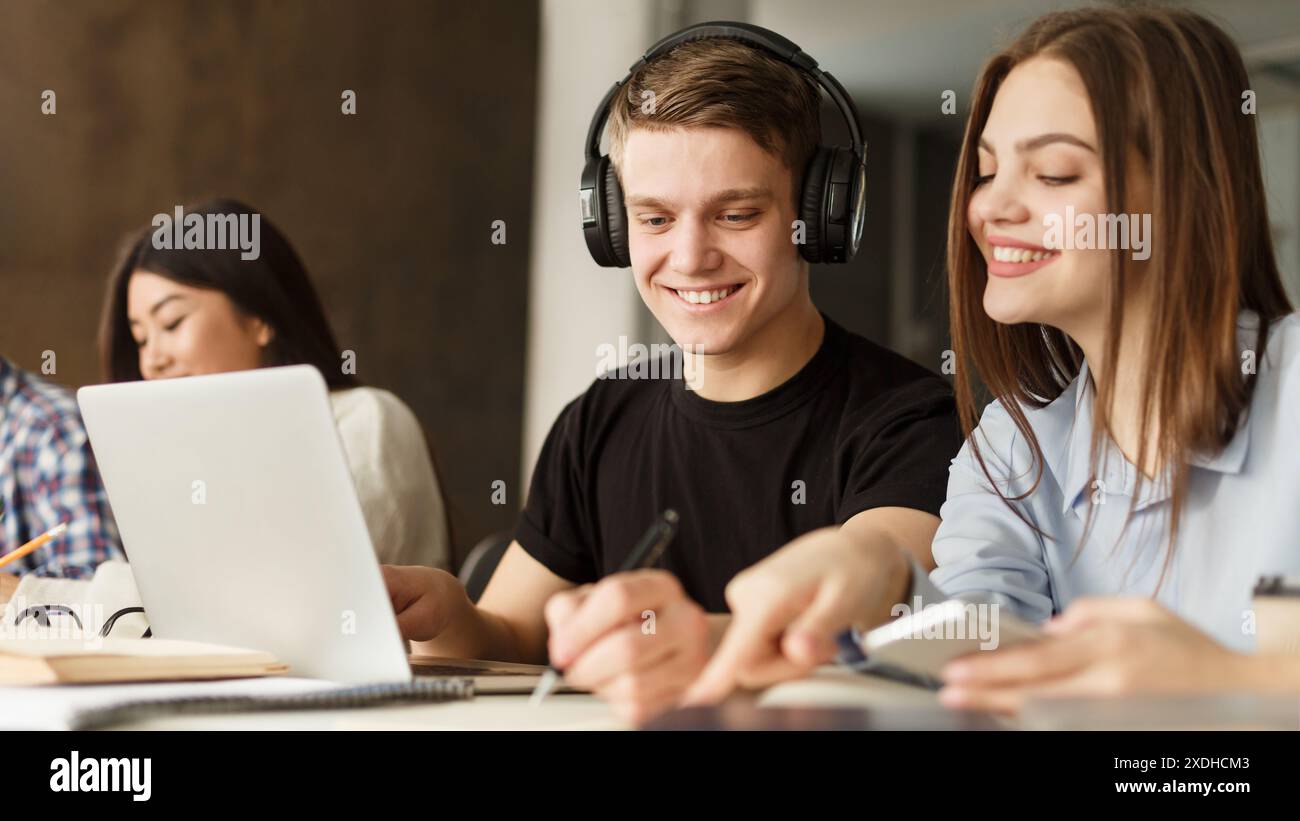Smiling Guy With Headphones Using Laptop in Group Study Session Stock Photo