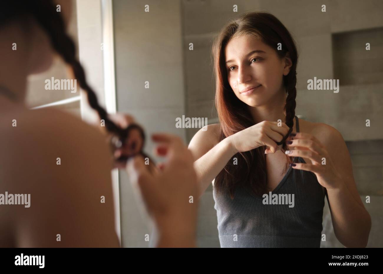 Teenage Girl Brushing And Braiding Her Hair In The Mirror As Part Of ...