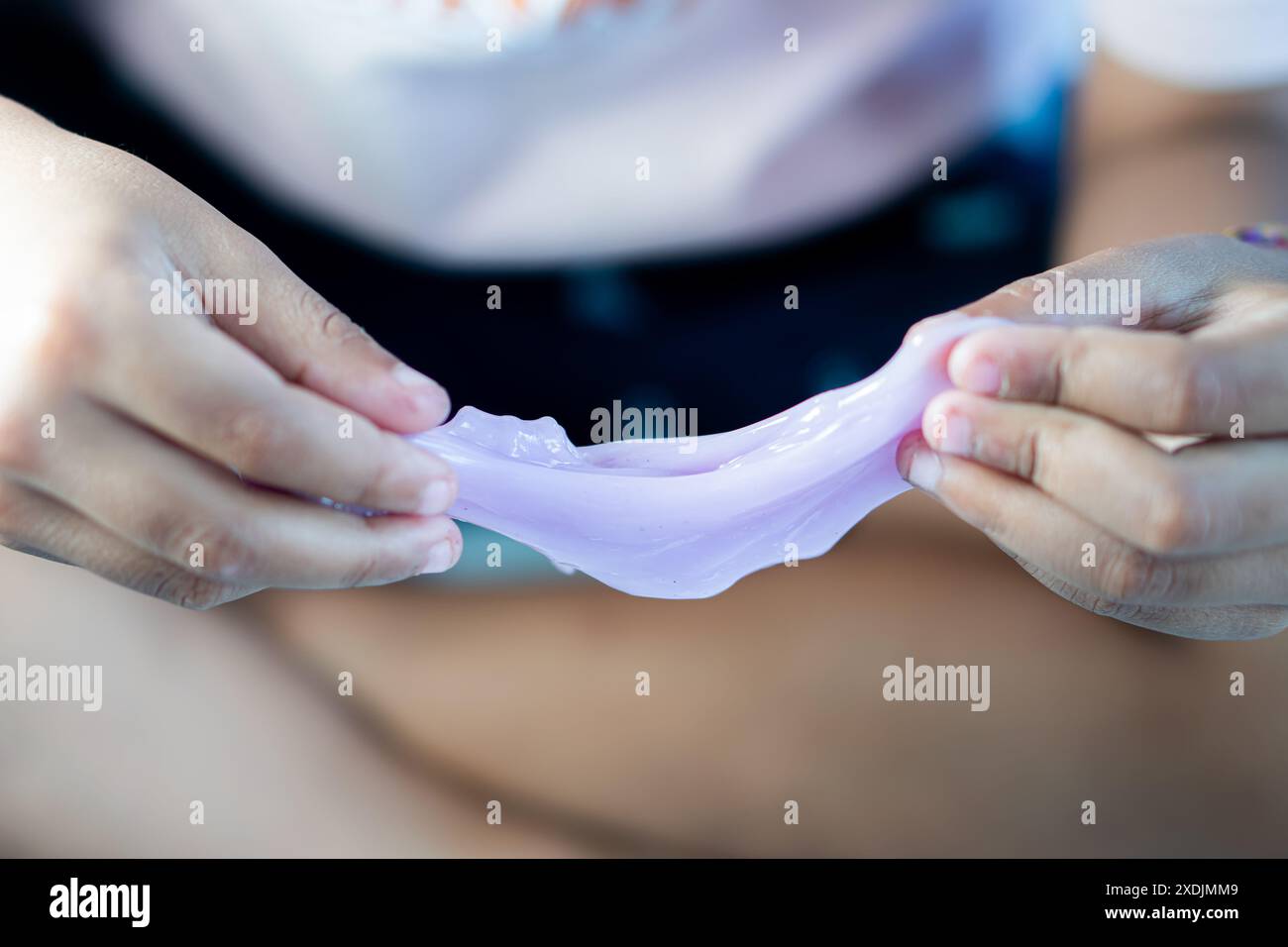 Close-up of hands playing with purple slime. Stock Photo