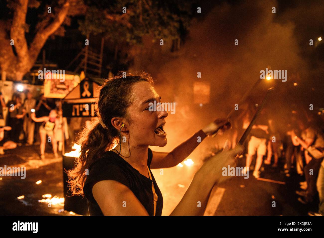 Israel. 22nd June, 2024. A protestor chants next to a bonfire in front ...