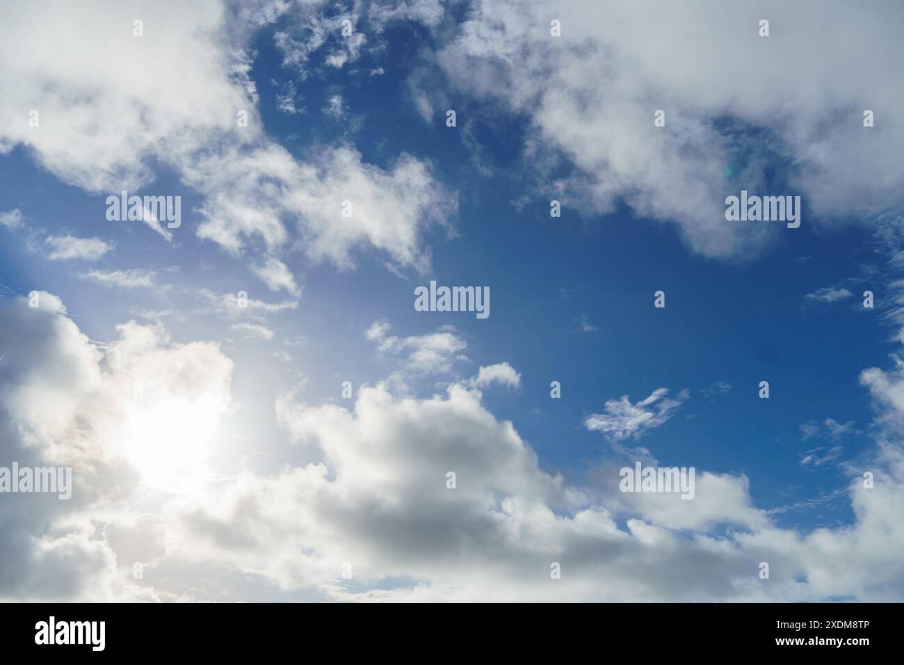 The sun shines through the clouds in a blue sky landscape Stock Photo ...