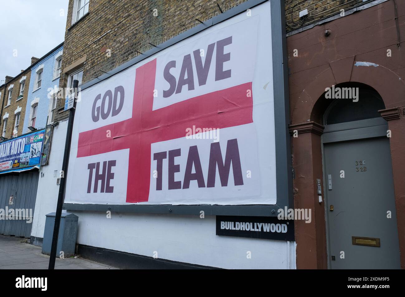 London, UK, 23rd June, 2024. A St George's flag billboard design with the words 'God Save the Team', by artist Corbin Shaw appears in a variety of different locations seeking to question what England represents today. Credit: Eleventh Hour Photography/Alamy Live News Stock Photo