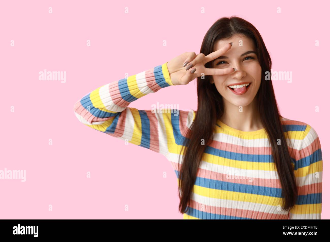 Young woman showing peace sign on pink background Stock Photo - Alamy