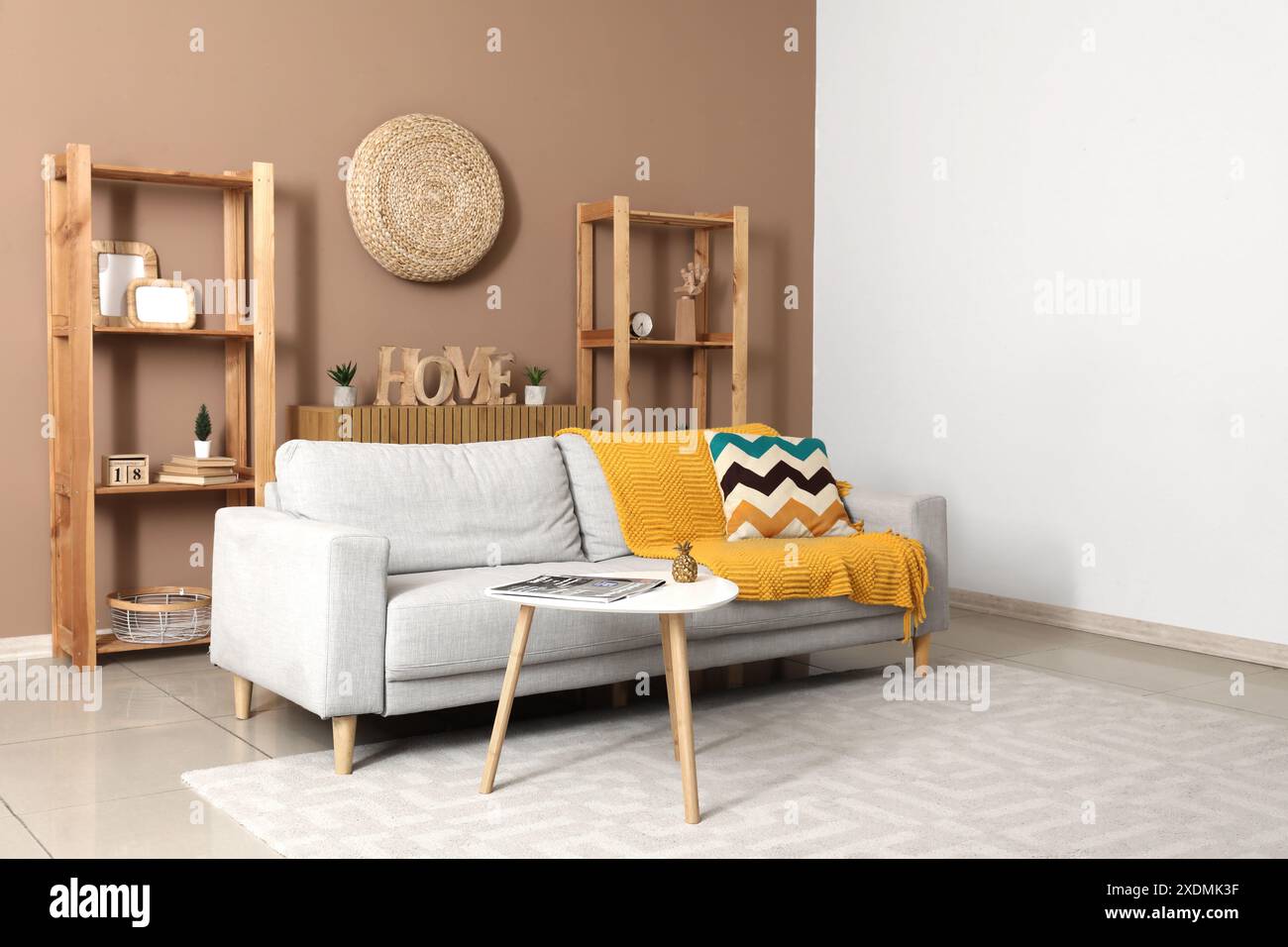 Interior of stylish living room with grey sofa, table and shelf units ...