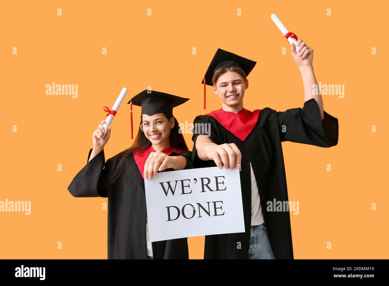 Happy graduate couple holding diplomas and paper sheet with text WE'RE ...
