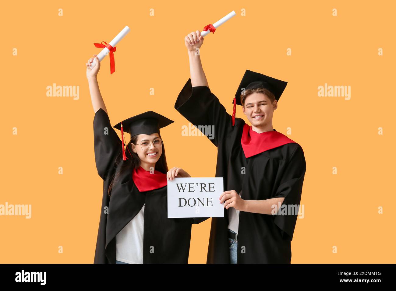Happy graduate couple holding diplomas and paper sheet with text WE'RE ...