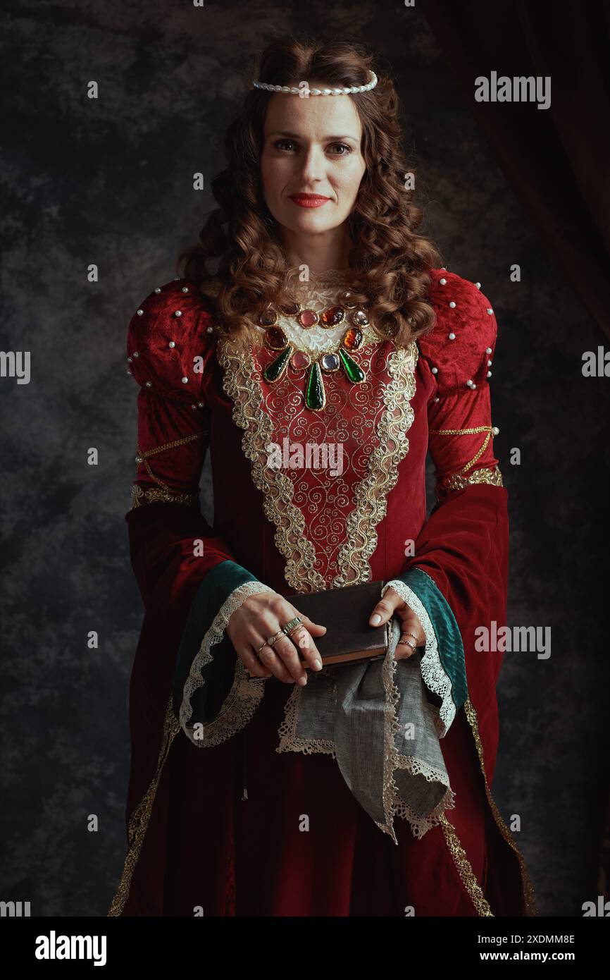 medieval queen in red dress with book and handkerchief on dark gray ...