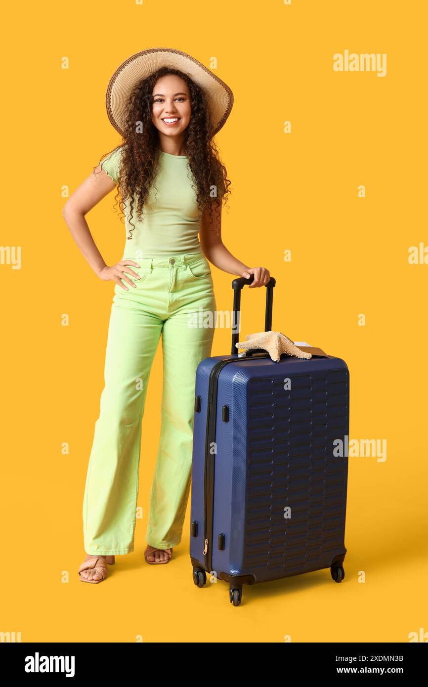 Happy young African-American woman in hat with suitcase and starfish on ...