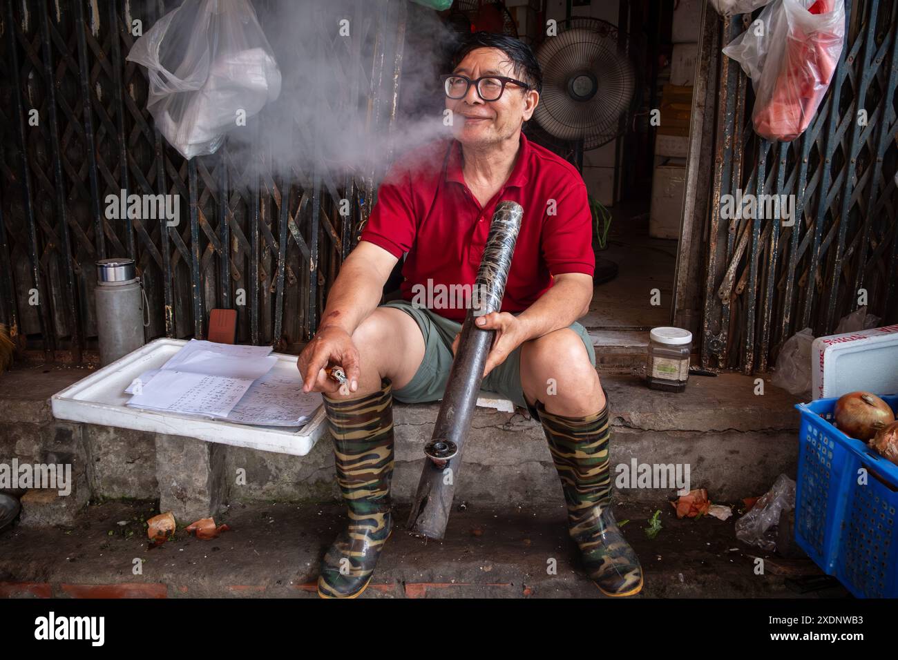 A man smokes a traditional bamboo pipe Stock Photo