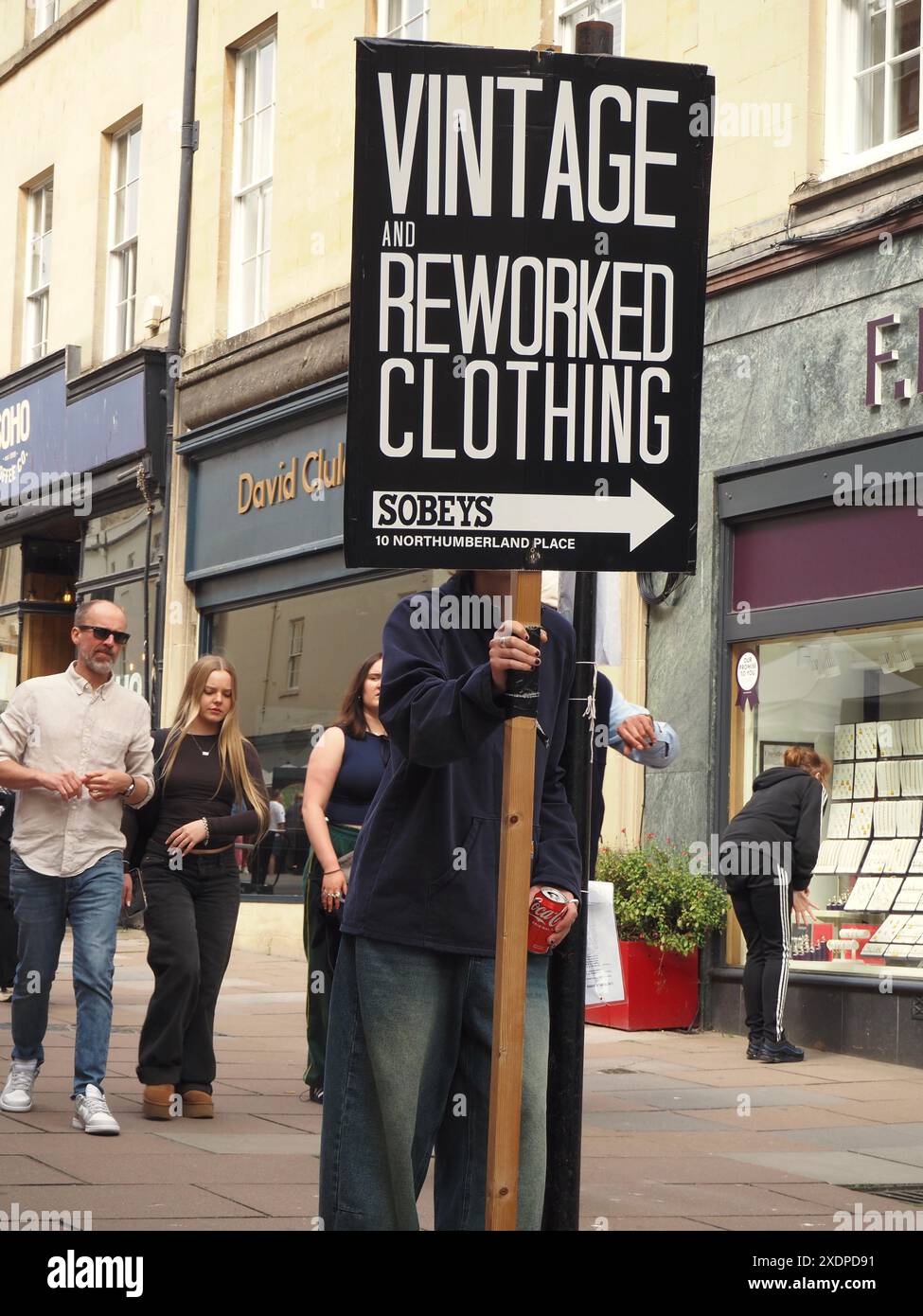Person in Union Street Bath holding arrow signboard advertising Sobeys vintage and reworked clothing. Recycling, reuse, repurposing Stock Photo