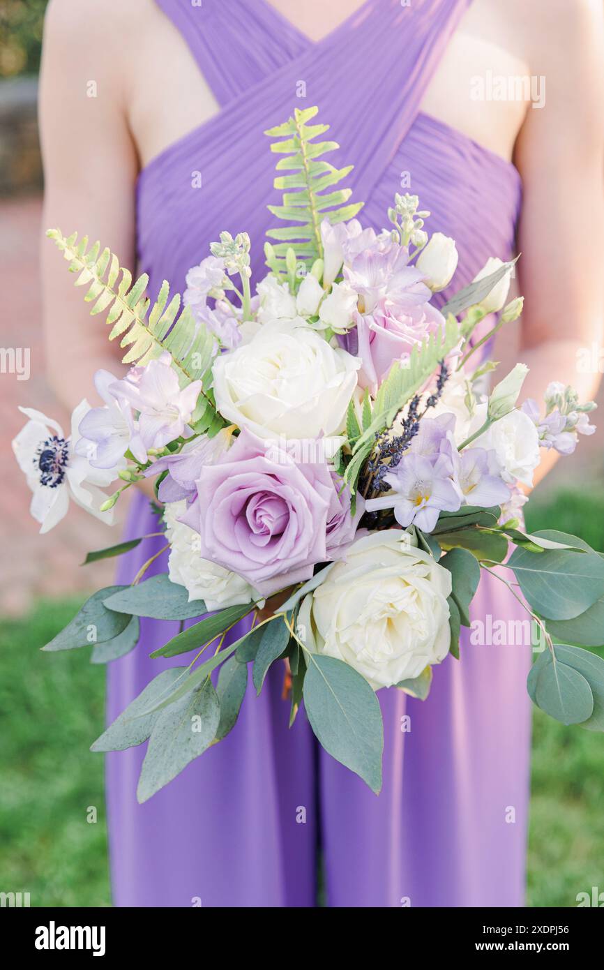 Bridesmaid holding bouquet with white, purple, and lavender flowers Stock  Photo - Alamy