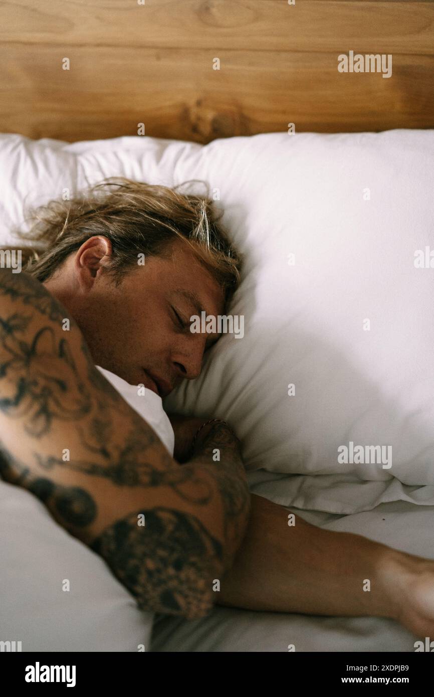 A young man sleeps sweetly in bed. Stock Photo