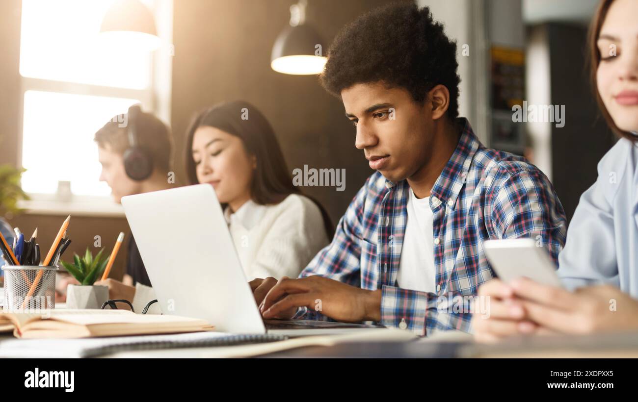 Diverse group of zoomers studying with tech in library Stock Photo