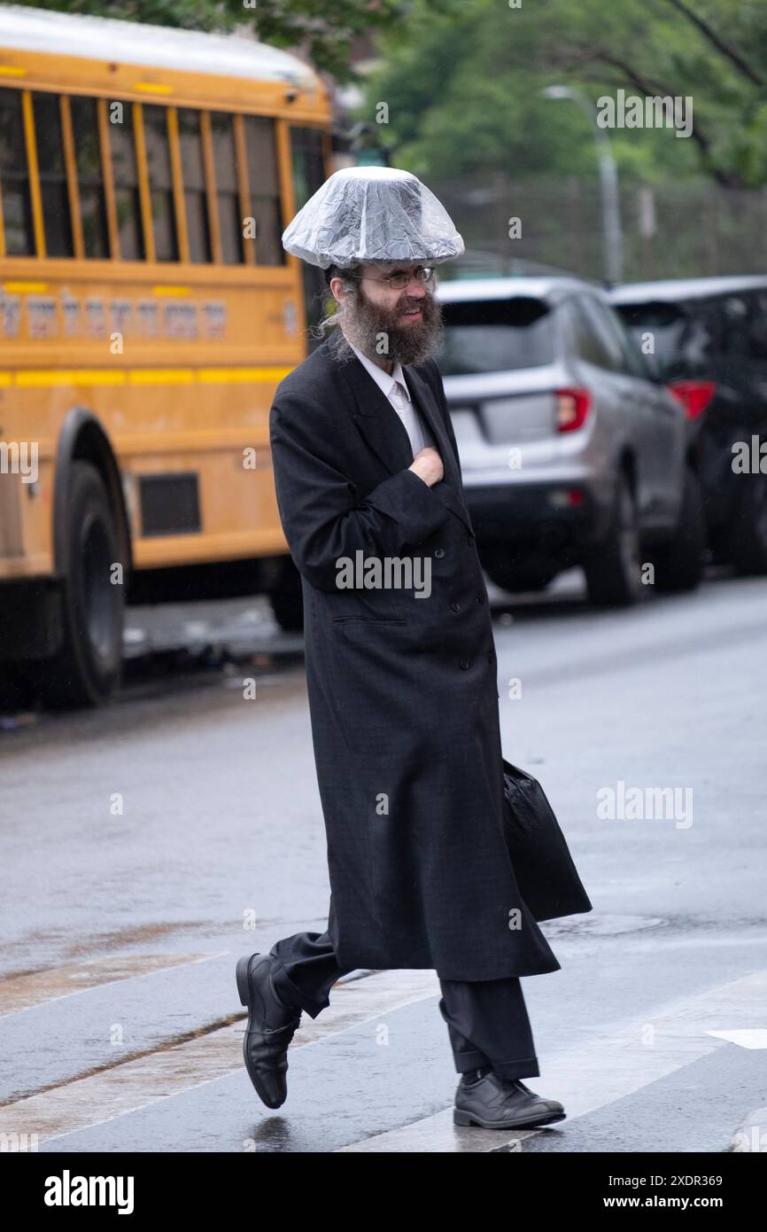 On a drizzly late spring morning an orthodox Jewish man wears an improvised hat protector. I Williamsburg, Brooklyn, New York. Stock Photo