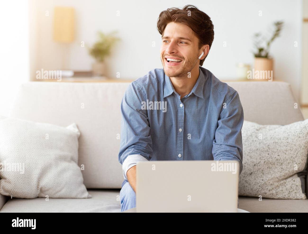 Man Laughing While Using Laptop on Couch Stock Photo