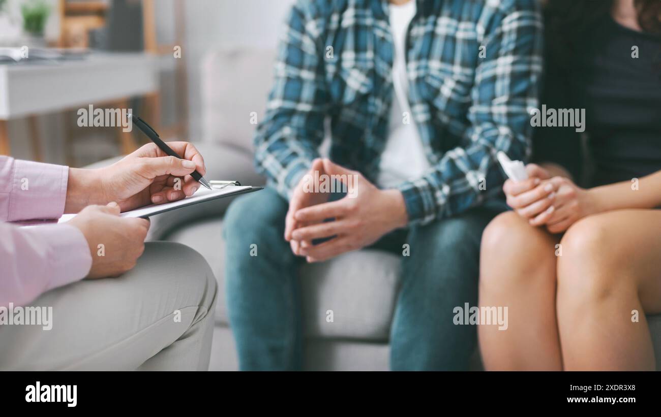 Therapist Taking Notes While Couple Sits on Couch During Session Stock Photo