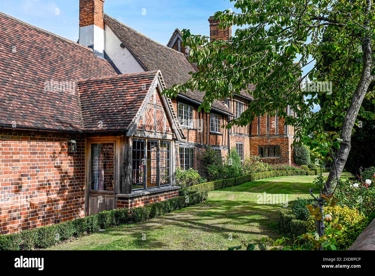 Porch entrance and lawn of gabled 16th century Tudor farmhouse in with later additions to make it a family home. Hertfordshire, England, UK. Stock Photo