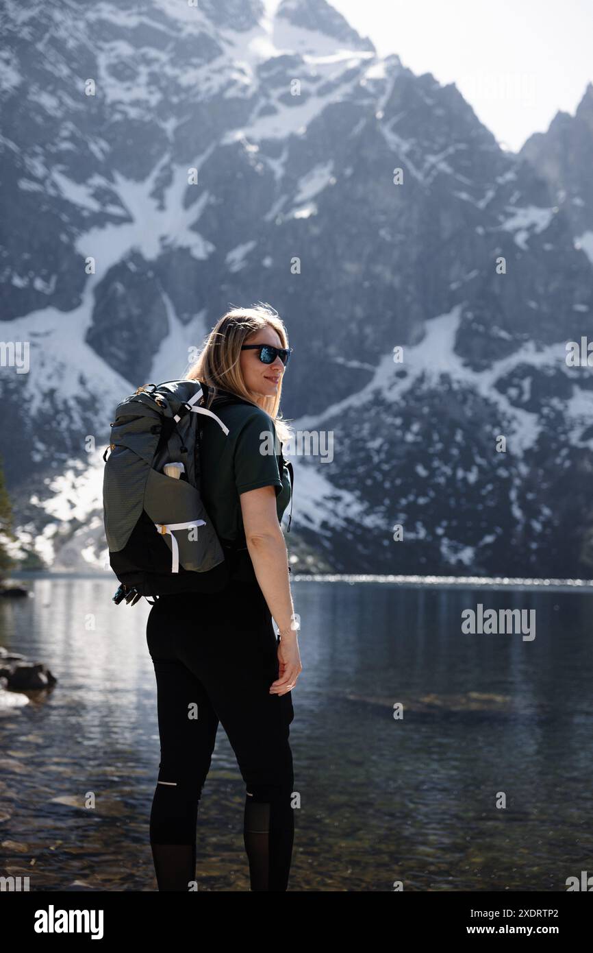 A traveler girl with a backpack enjoys the stunning view of a mountain ...
