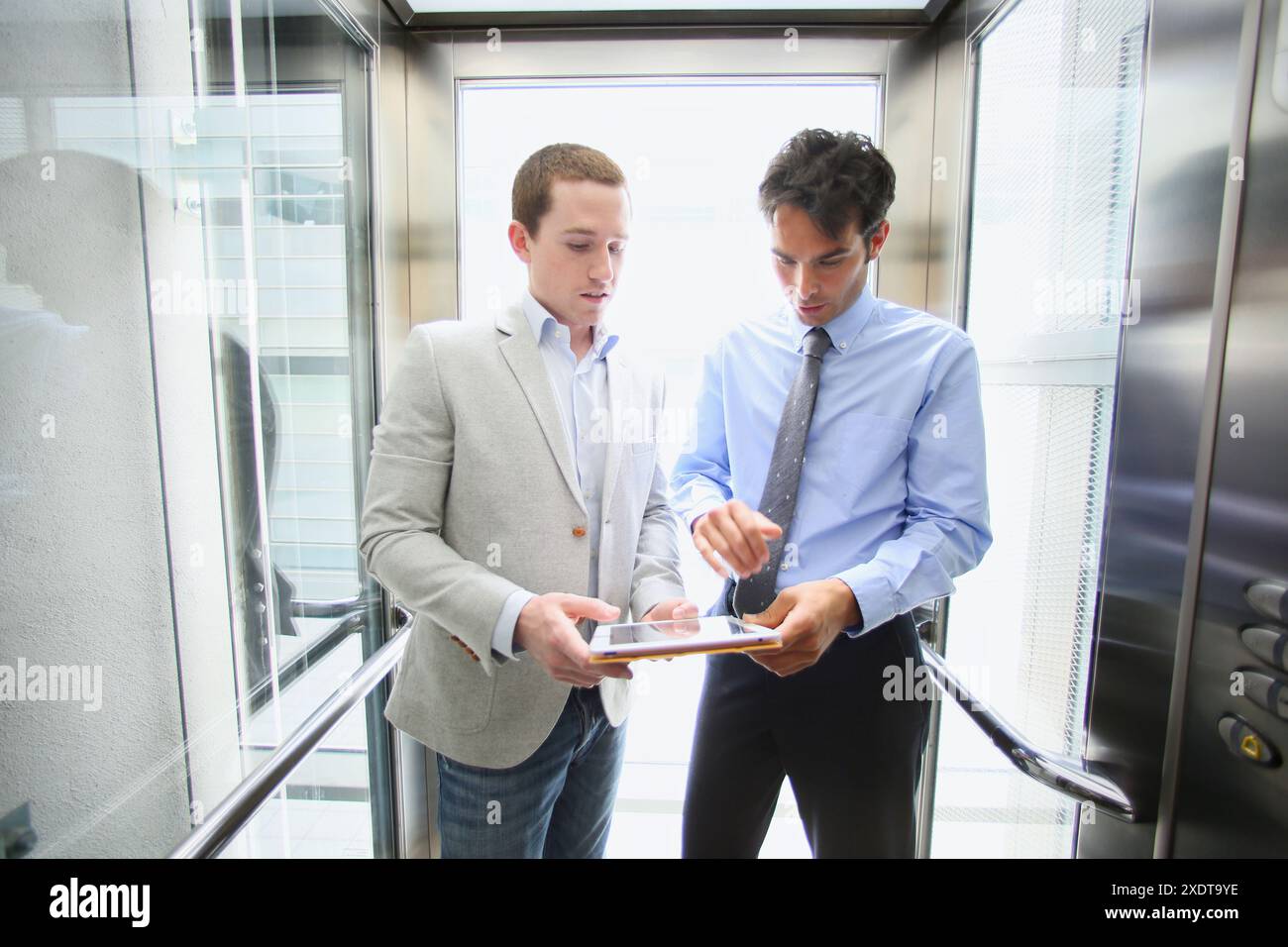 Two executives in elevator, using a digital tablet Stock Photo