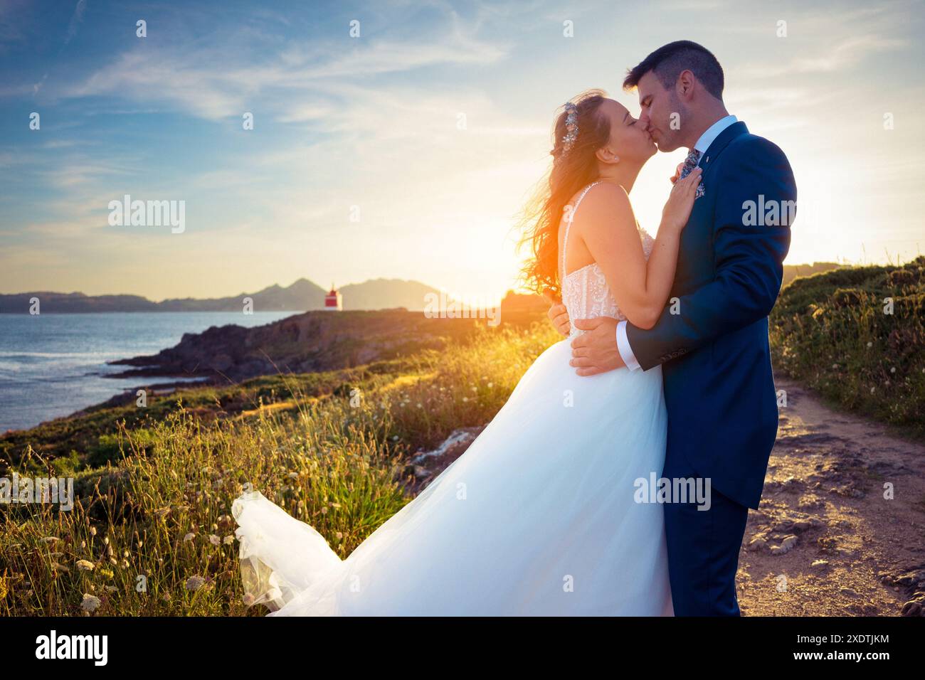 Portrait of groom and bride kissing each other near the ocean at sunset ...