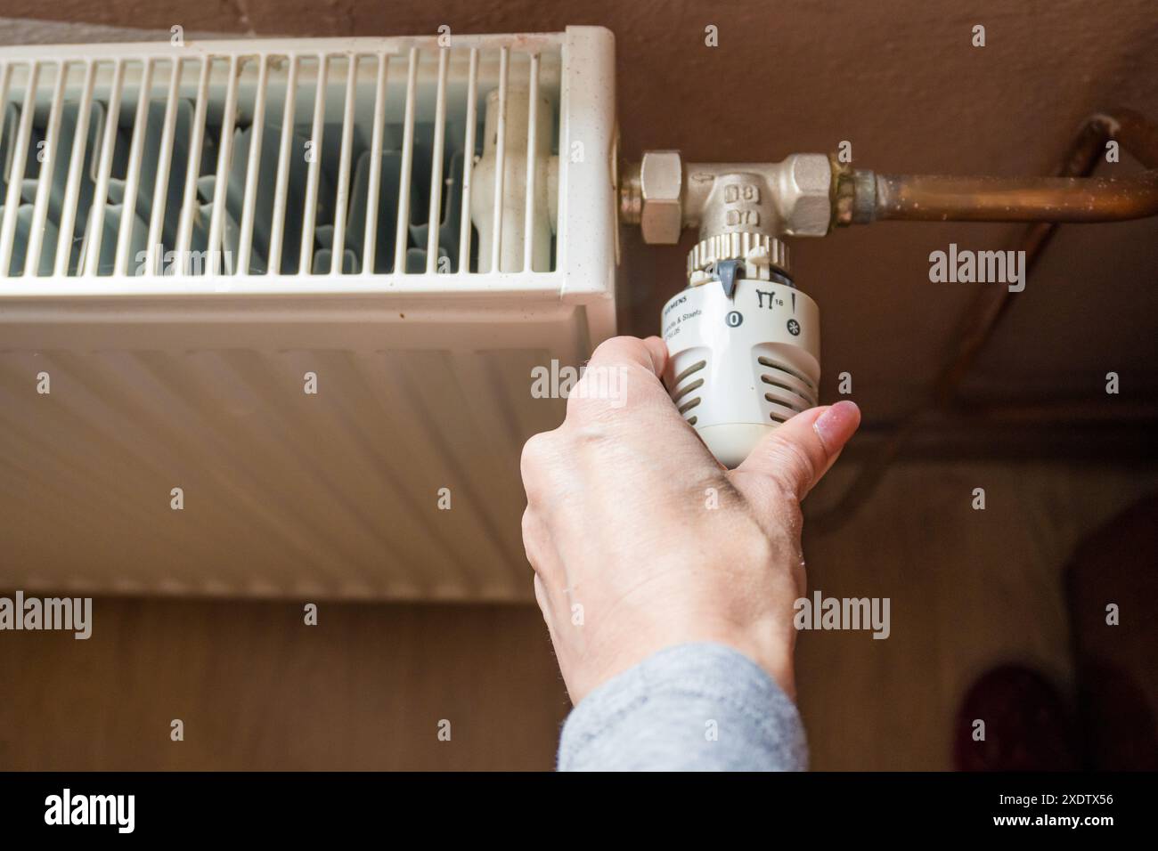 Hand adjusting temperature on heating radiator thermostat, Economy concept. Turning heat