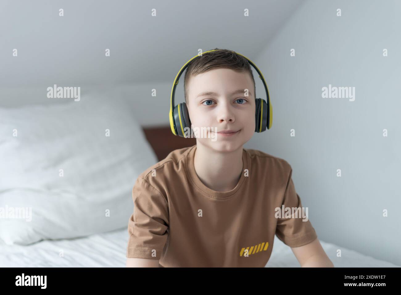 closeup of boy with blue eyes listening music with green headphones indoor Stock Photo