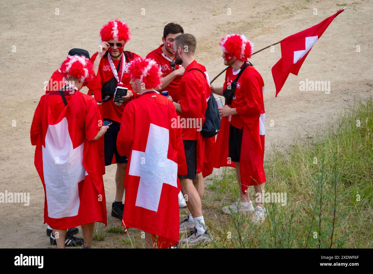 Swiss fans in red outfits, proudly displaying national symbols and flags, await UEFA EURO 2024 match, Frankfurt, Germany – June 23, 2024 Stock Photo