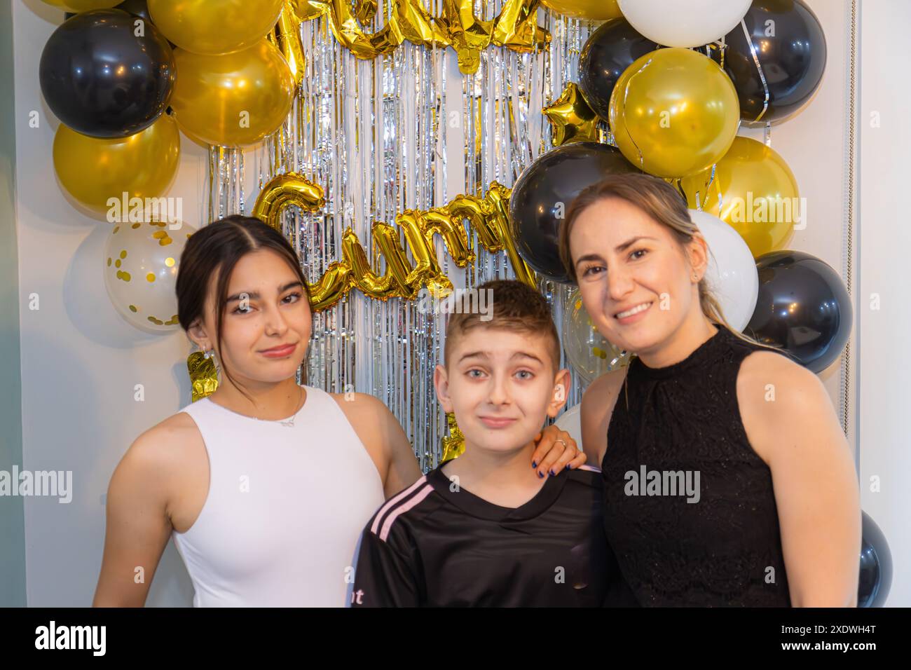 Young birthday girl accompanied by her little brother and mother. Stock Photo