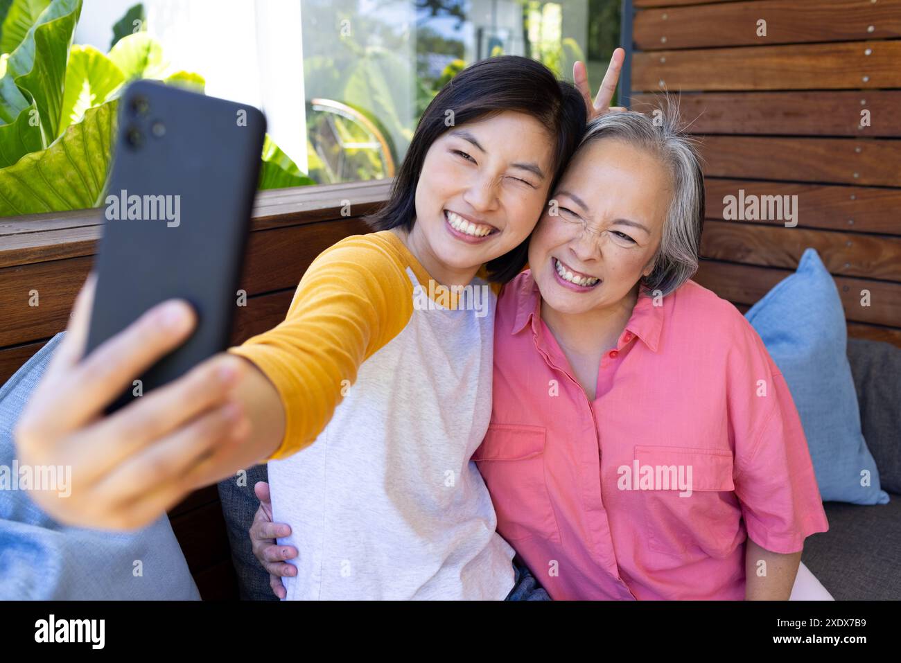 Taking selfie, Asian woman and senior woman smiling together on couch Stock Photo