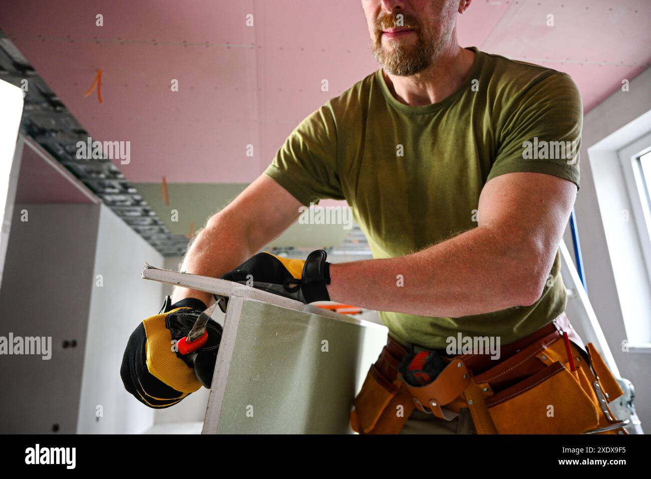 Construction worker carefully cutting drywall using a utility knife