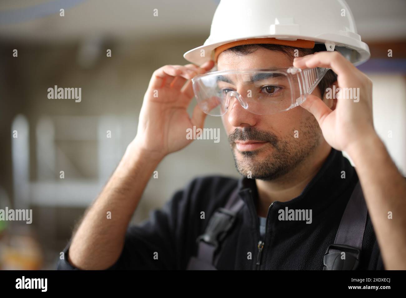 Construction worker putting protective glasses before work in a house under reform Stock Photo