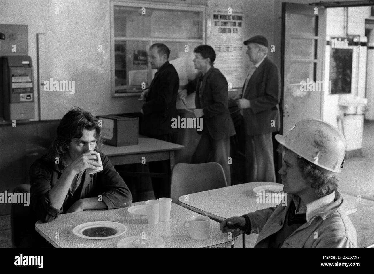 Coal miners in the canteen drinking a cup of tea. Three miners queue up at the colliery Concessionary Fuel Office. South Kirkby Colliery, Yorkshire, England 1979 1970s UK HOMER SYKES Stock Photo
