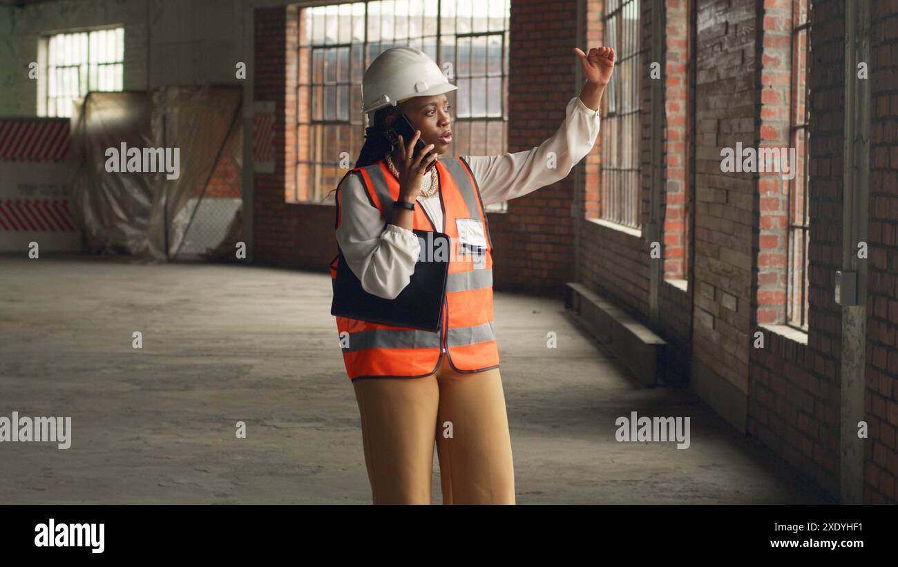 Black Female Engineer Inspecting Construction Site and Talking on Phone Stock Photo
