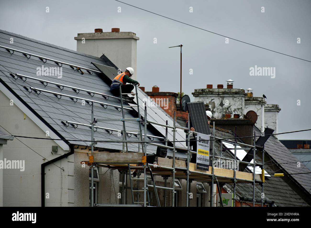 Workers installing solar panels on a roof in Ardara, County Donegal, Ireland. Stock Photo