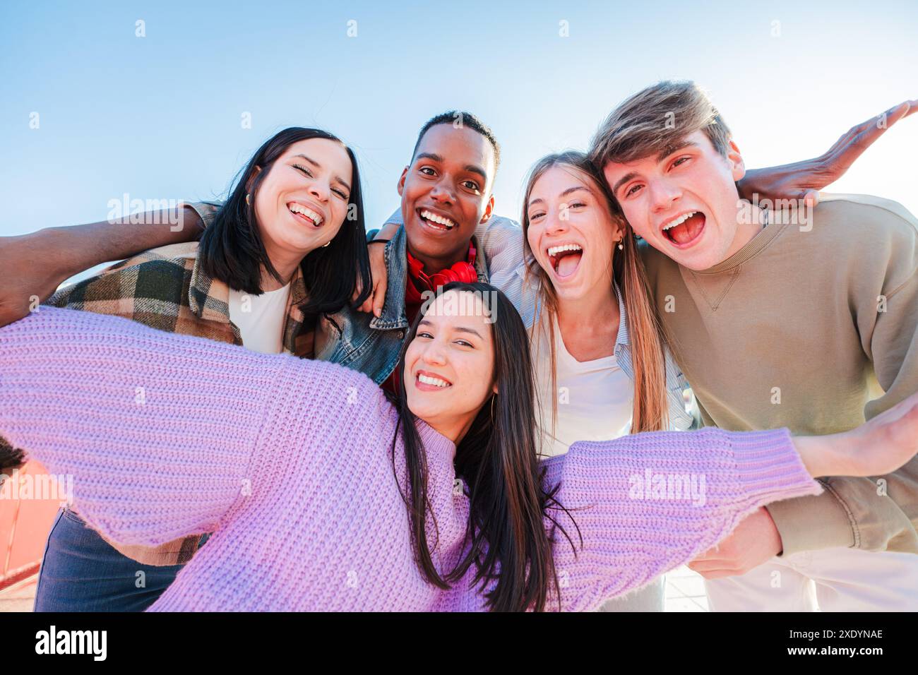 Group of real multiracial teenagers having fun together and posing for a portrait. Young friends smiling and laughing. Multiethnic people bonding outside with positive and friendly expression. High quality photo Stock Photo